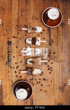 Hausgemachte Espresso Macchiato und Latte Macchiato Eis am Stiel mit Kaffeebohnen auf hölzernen Hintergrund Stockfoto