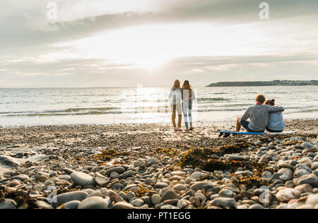 Freunde mit Surfbrett den Sonnenuntergang am Strand Stockfoto