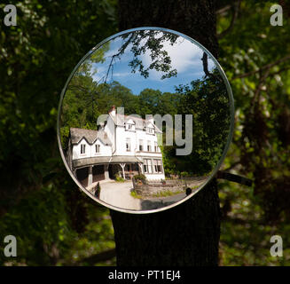 Große weiße Land Haus und Bäume am Rande des Rydal Wasser, Lake District, der in einem gebogenen Spiegel Schild an einem Baum gegenüber wider, für Sicherheit Stockfoto