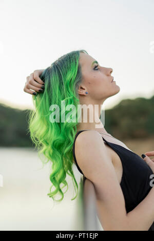 Profil von junge Frau mit gefärbten grüne Haare und Augenbrauen in der Natur Stockfoto