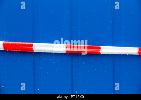 Rot und Weiß Warnband auf einem blauen Hintergrund aus Stahl Stockfoto