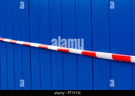 Rot und Weiß Warnband auf einem blauen Hintergrund aus Stahl Stockfoto