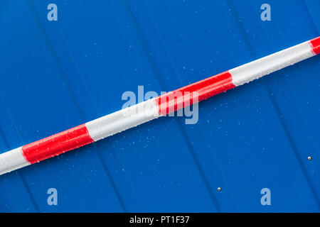 Rot und Weiß Warnband auf einem blauen Hintergrund aus Stahl Stockfoto