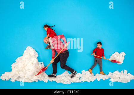 Vater und Kinder Schneeschaufeln Stockfoto