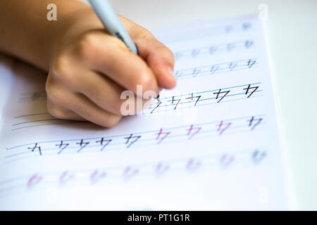 Hand des kleinen Mädchens Schreiben von Zahlen, die in der übung Buch, close-up Stockfoto