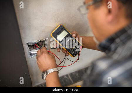 Man Kontrolle Steckdose mit Strom Stockfoto