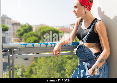 Tätowierte junge Frau stand auf dem Balkon mit Blick auf Abstand Stockfoto