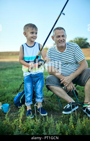 Großvater und Enkel Angeln zusammen am Seeufer Stockfoto