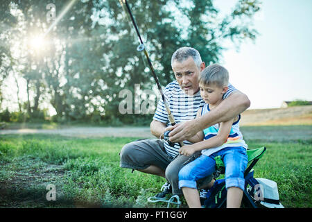 Großvater und Enkel Angeln zusammen am Seeufer Stockfoto