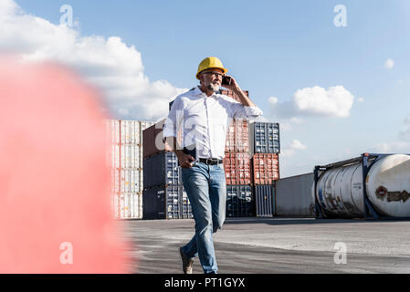 Unternehmer im Cargo Hafen, weraing Schutzhelm, mit Smartphone und digitale Tablet Stockfoto