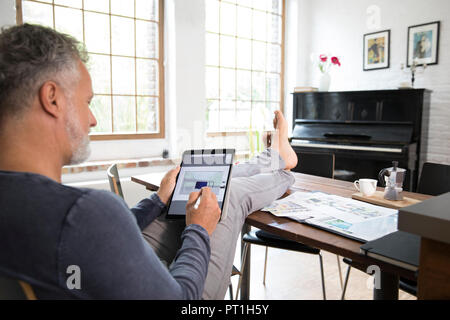 Reifer Mann laufen, das von seinem Home Office mit Füße hochlegen, auf Tablet Stockfoto