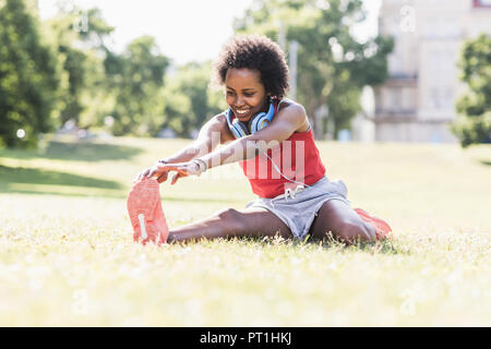 Junge Frau, die sich auf der Wiese im Park Stockfoto