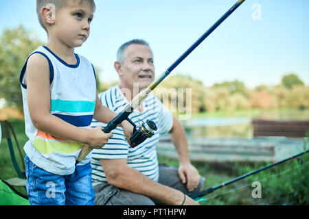 Little boy Angeln zusammen mit seinem Großvater am Seeufer Stockfoto