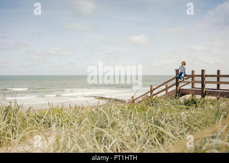 Frau sitzt auf der Zaun am Strand, relaxen am Meer Stockfoto