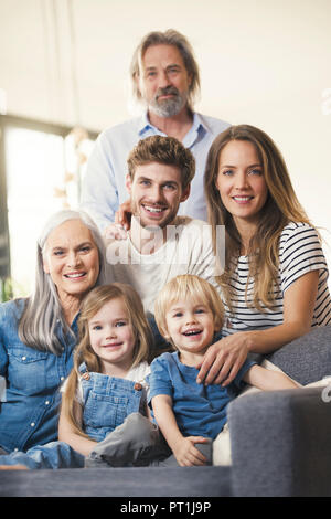 Erweiterte Familie sitzt auf der Couch, glücklich lächelnd Stockfoto