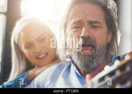 Senior Gitarre spielen und singen laut für seine Frau Stockfoto