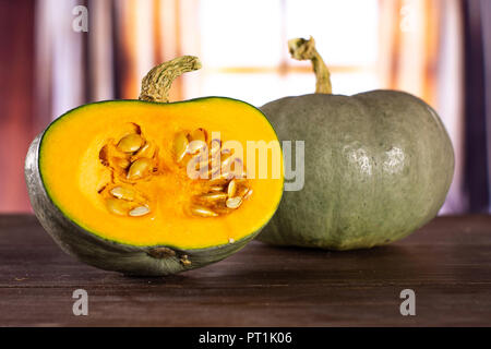 Eine ganze Hälfte von frischem Blau Grau Kürbis Nagy dobosi Sorte mit seidenen Vorhängen hinter Stockfoto