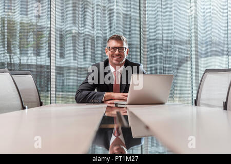 Polen, Warzawa, lächelnden Geschäftsmann sitzt am Konferenztisch in hotel Stockfoto