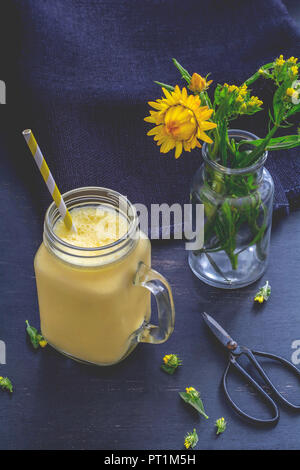 Glas mango Joghurt Smoothie und ewige Blumen in Vase Stockfoto