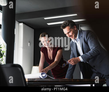 Lächelnd Business-frau und Geschäftsmann im Büro diskutieren Plan auf Schreibtisch Stockfoto