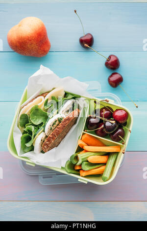 Gesunde Schule Essen in einer Lunchbox, vegetarisches Sandwich mit Käse, Salat, Gurke, Ei und Kresse, geschnittene Karotten und Sellerie, Kirschen und Birnen Stockfoto