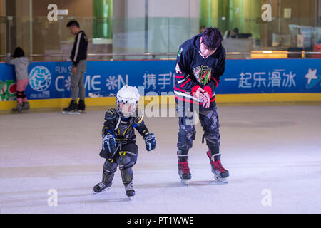 Kunming, Provinz Yunnan in China. 5. Okt, 2018. Ein Coach beauftragt ein Kind in Skaten in eine Eisbahn während der einwöchigen Nationalen Tag Urlaub in Kunming, der Hauptstadt der Provinz Yunnan im Südwesten Chinas, Oktober 5, 2018. Credit: Hu Chao/Xinhua/Alamy leben Nachrichten Stockfoto