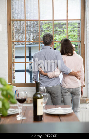 Reifes Paar stehend in der komfortablen Loft, schauen aus dem Fenster, Rückansicht Stockfoto