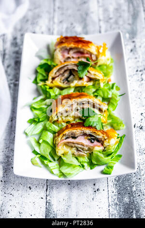 Swiss roll, Blätterteig mit Wurst, Fleisch, Käse, Zwiebel, Petersilie und Salat auf Teller Stockfoto