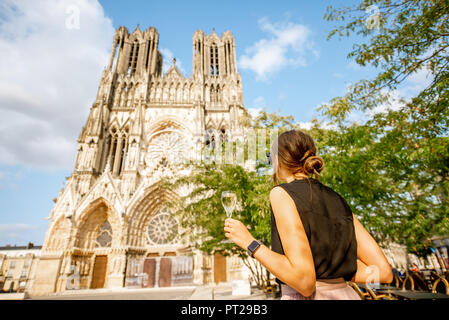 Junge Frau mit Champagner steht vor der Kathedrale in Reims City, die Hauptstadt der Champagne Wein Region, Frankreich Stockfoto