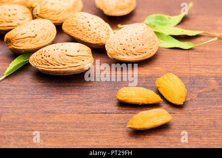 Rohe Mandeln, geschält, mit Schale, Haut (almendrucos) und Mandel Blätter. Auf dunklen Hintergrund. Stockfoto