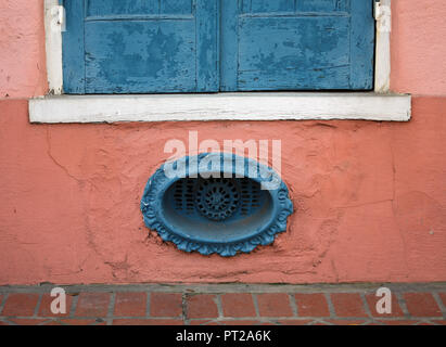 Detail der Roten Wand mit blau Metall Vent und weissen Fensterrahmen mit blauen Fensterläden geschlossen Stockfoto