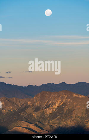 Mond über Mount Aspiring NP von Roys Peak Lookout bei Sonnenuntergang, Wanaka, Queenstown Lakes District, Region Otago, Südinsel, Neuseeland, Stockfoto