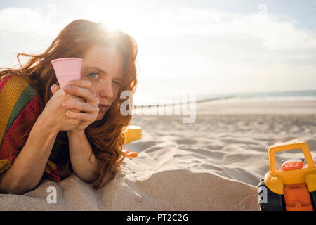 Rothaarige Frau am Strand mit Strand Spielzeug Stockfoto