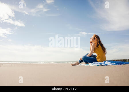 Frau sitzt am Strand und genießen die Sonne Stockfoto