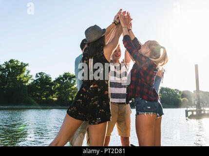 Eine Gruppe von Freunden, die ihre Hände zusammen am Flußufer Stockfoto