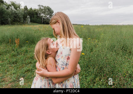Zwei kleine Schwestern umarmen auf einer Wiese Stockfoto