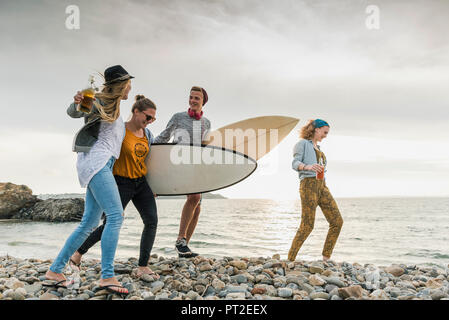 Gerne Freunde mit Surfboards Wandern auf steinigem Strand Stockfoto