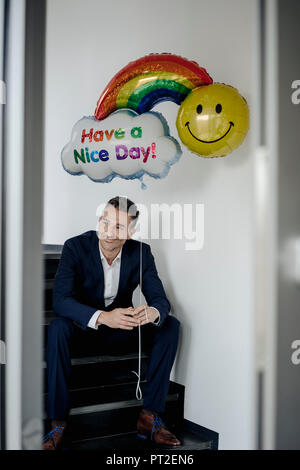 Lächeln, Geschäftsmann, sitzen auf der Treppe holding Ballon Stockfoto