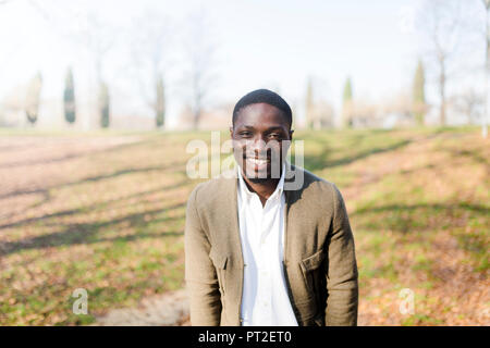 Portrait ogf junger Mann im Park, tragen Jacke, lächelnd Stockfoto