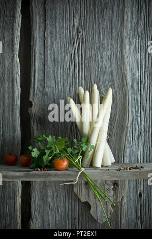 Bündel weißer Spargel, Tomaten, Petersilie und Pfeffer vermischt auf Holz Stockfoto