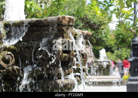 Niño vestido con camiseta Blanca posando Junto eine enorme Escultura de Rostro de Farbe verde en un día Soleado en el centro de Guadalajara Stockfoto