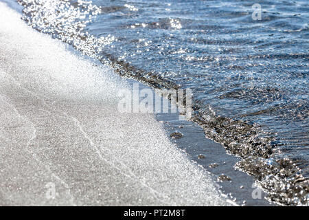 Kleine Wellen brechen in der Hintergrundbeleuchtung auf dem Sandstrand von Palombaggia, Korsika Stockfoto