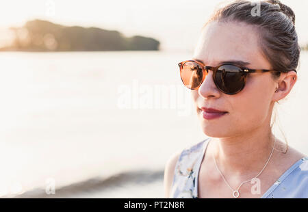 Junge Frau eine Sonnenbrille trug am Flussufer Stockfoto