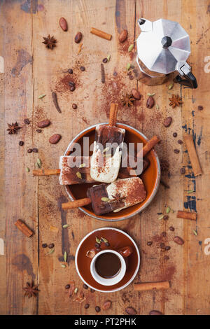 Hausgemachte Espresso und weiße Schokolade Eis am Stiel mit winterlichen Gewürzen, Tasse Espresso und Espresso maker auf Holz- Hintergrund Stockfoto