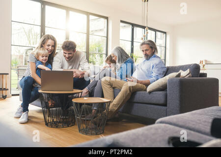 Erweiterte Familie sitzt auf der Couch, mit mobilen Geräten Stockfoto