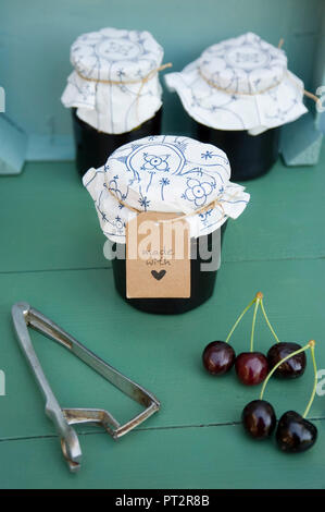 Gläser selbstgemachte Kirsche Konfitüre, Kirschen und pit Remover Stockfoto
