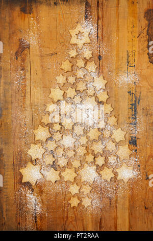 Sternförmige Kekse bilden Weihnachtsbaum auf Holz- Hintergrund Stockfoto
