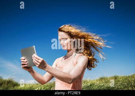 Niederlande, Zandvoort, die Frau in den Dünen mit Tablet Stockfoto