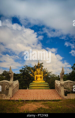 Wunderschöne goldene Buddha Statue mit sieben Phaya Naga Köpfe unter weißen Wolken und blauer Himmel. Outdoor golden sitzender Buddha Bild geschützt durch