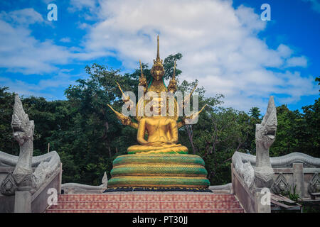 Wunderschöne goldene Buddha Statue mit sieben Phaya Naga Köpfe unter weißen Wolken und blauer Himmel. Outdoor golden sitzender Buddha Bild geschützt durch